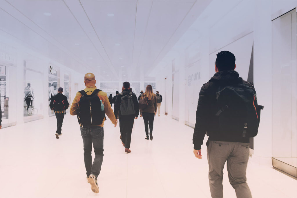 A groups of school students walking in a white hallway.
