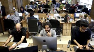 A group of employees working on their computers in an office with an open concept.