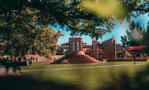 A university campus with students walking around in the foreground.