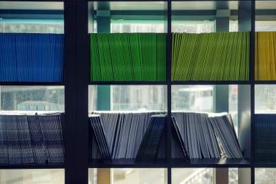 A closeup of a bookcase filled with blue, green, and yellow folders.